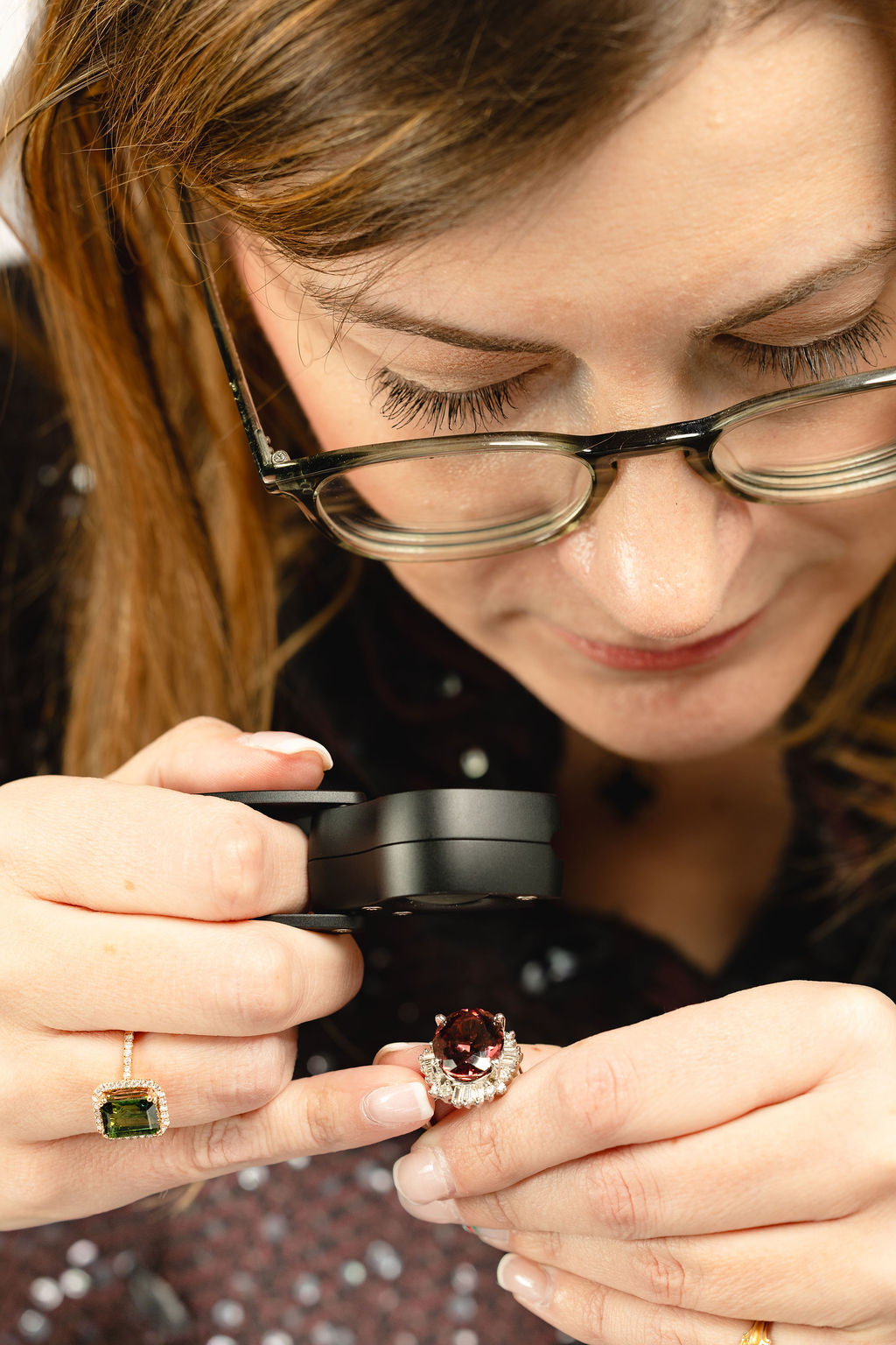Stephanie Daugherty examining a gemstone ring with a loupe